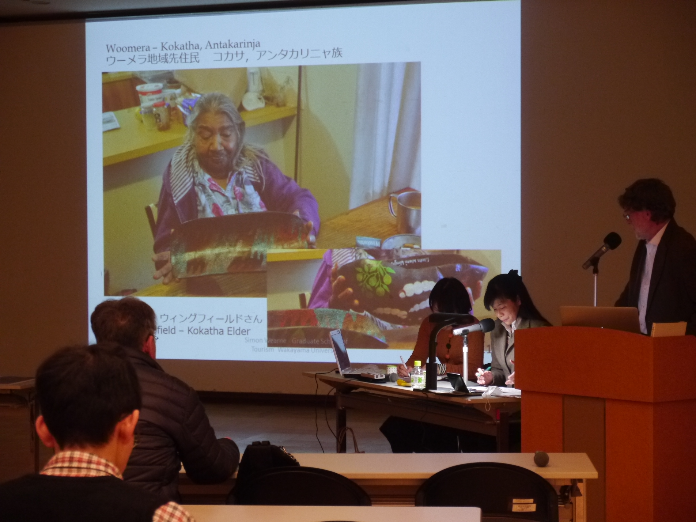 スクリーンの横に立って話をするサイモン・ワーン特任助教