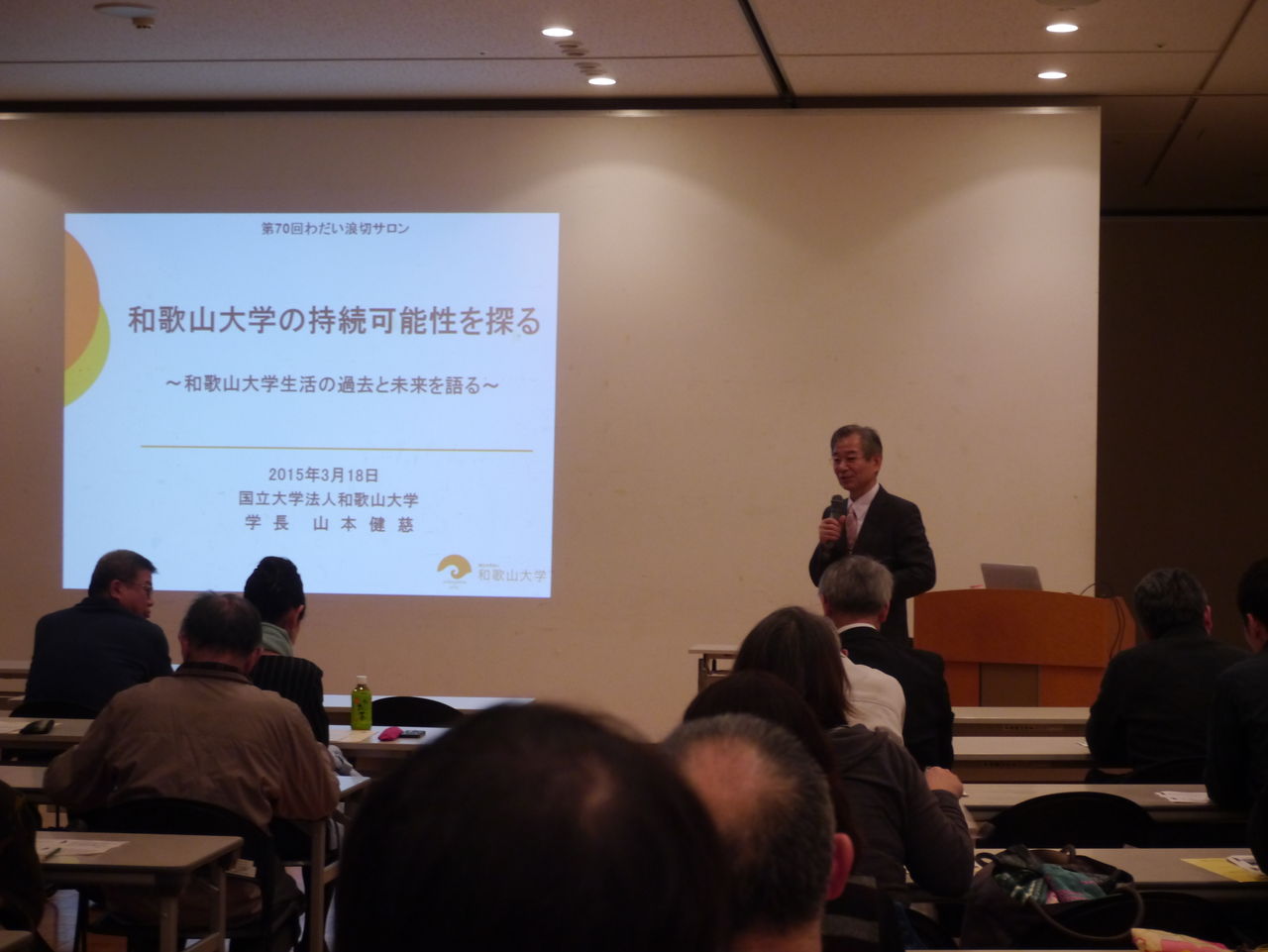 スクリーンの横に立って話をする山本健慈学長 スクリーンの横に立って話をする山本健慈学長