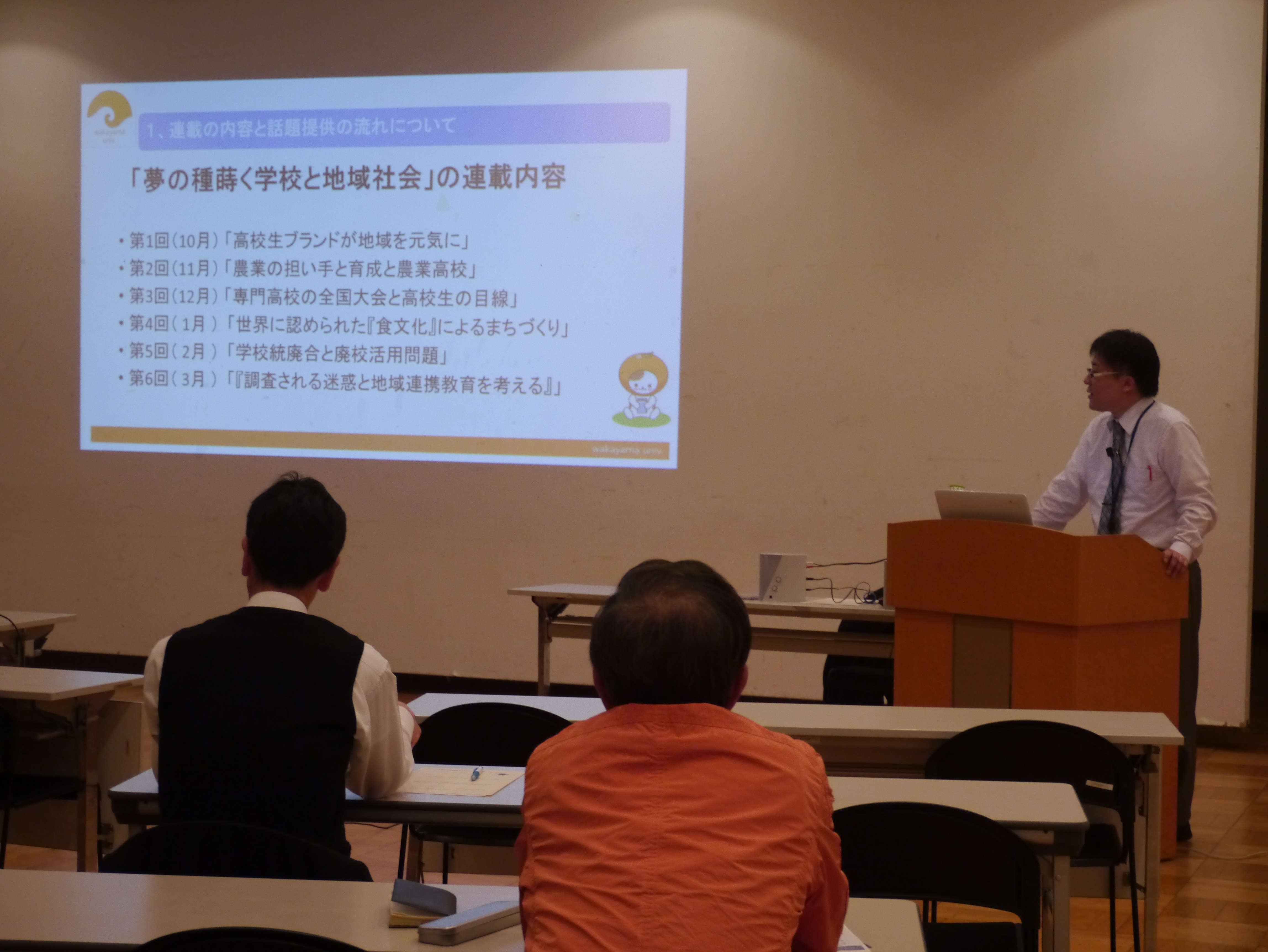 スクリーンの横に立って話をする阿部英之助特任准教授