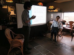 スクリーンの周りに立つ田代優秋先生と西川一弘先生