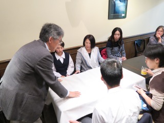 テーブルで実験をする石塚亙先生を見る参加者