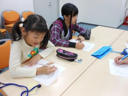 机で台詞と動作を書く子供達