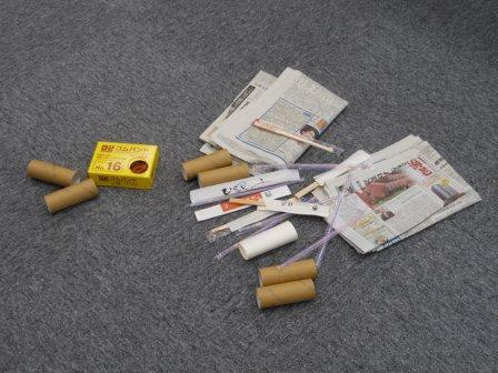 床に置かれた新聞紙やトイレットペーパーの芯など