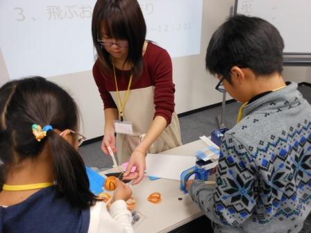 机の周りに集まって作業をする様子