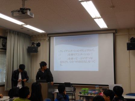 スクリーンの横に立って話す先生