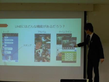 スクリーンの横に立って話す先生 スクリーンの横に立って話す先生