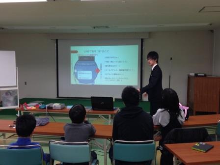 スクリーンの横に立って話す先生 スクリーンの横に立って話す先生