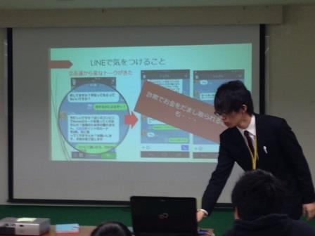 スクリーンの横に立って話す先生 スクリーンの横に立って話す先生