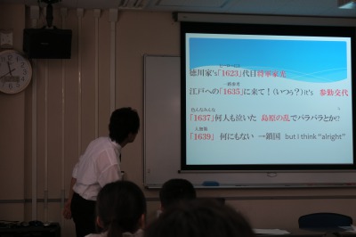 スクリーンを見ながら話す先生