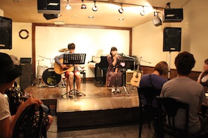 ステージでギターを演奏する男性と歌う女性